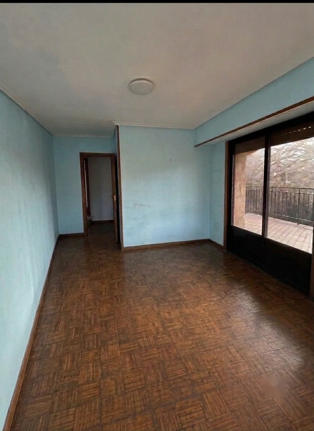 La misma habitación antes de la reforma: paredes pintadas y suelo de parqué antiguo