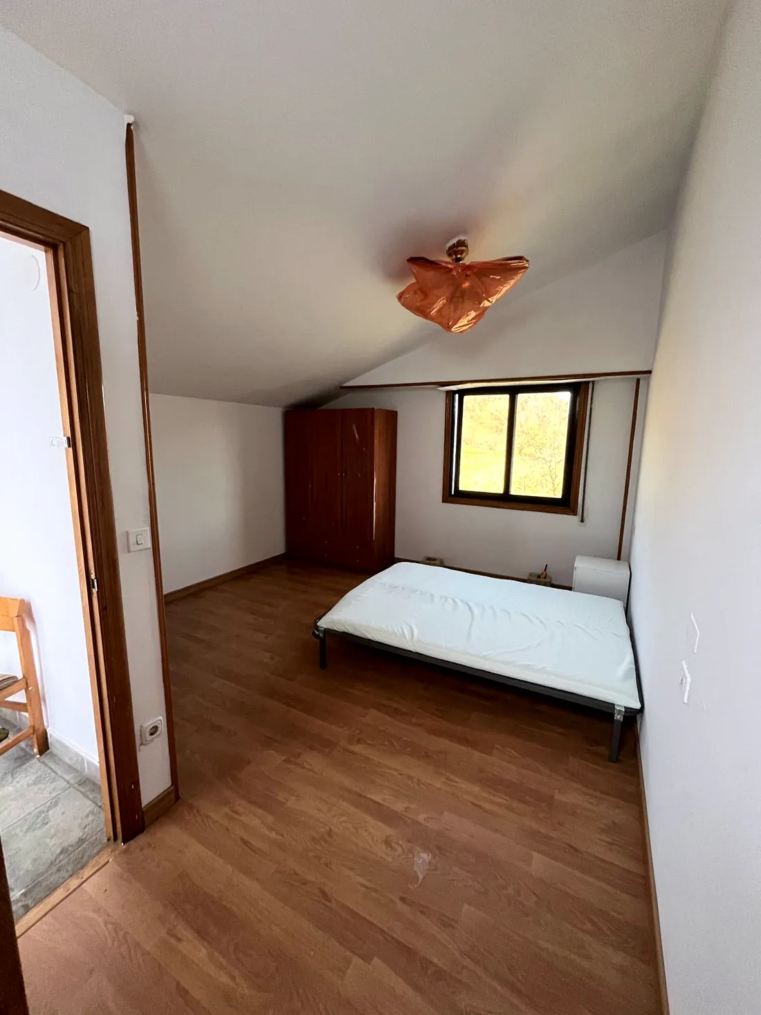 Habitación abuhardillada con ventana a zona verde