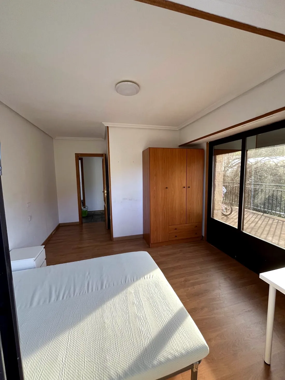 La misma habitación ya reformada, con suelo nuevo, paredes claras y mobiliario